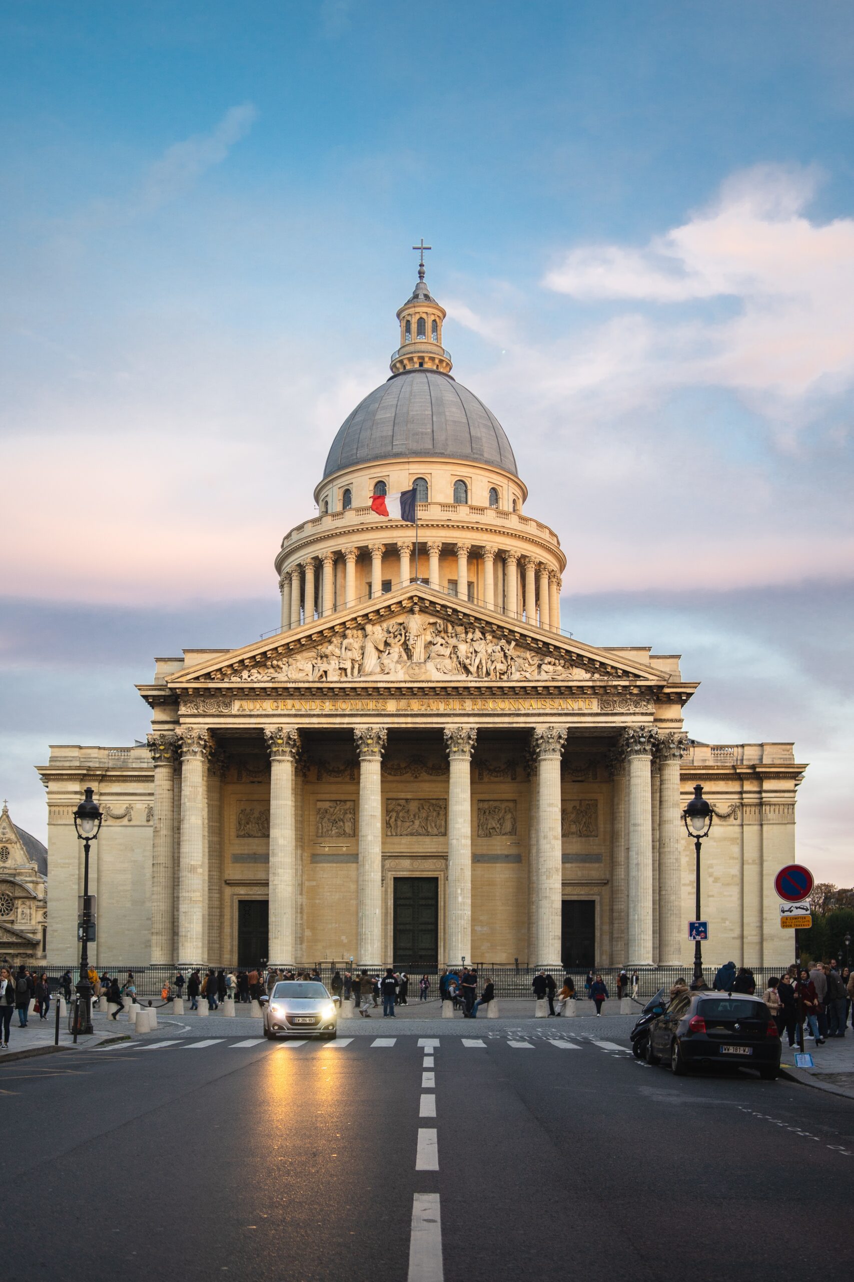 The Pantheon surrounded by people under a cloudy sky during sunset in Paris in France